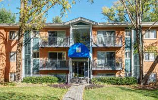 front view of an apartment building with trees and grass