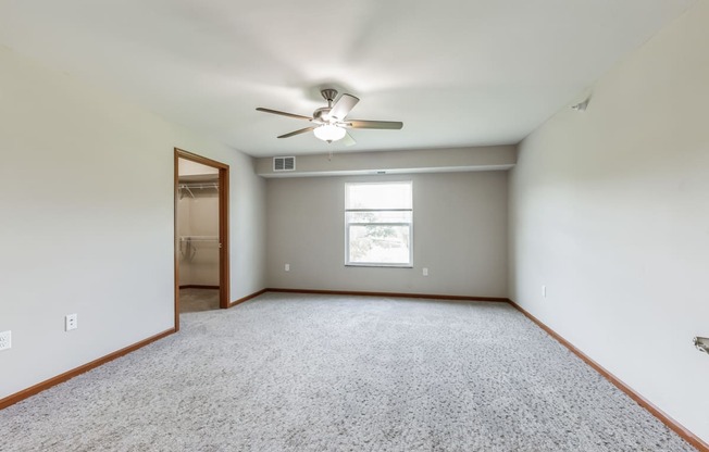 an empty living room with a ceiling fan and a window