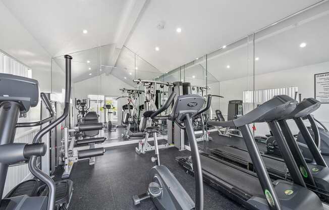 a gym with cardio equipment and mirrors on the wall