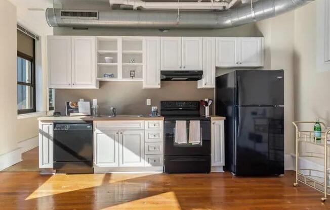 A kitchen with black appliances and white cabinets.