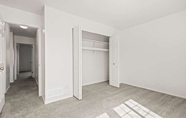 A bedroom with a carpeted floor and a white closet at Tanglewood Apartments, Oak Creek, WI