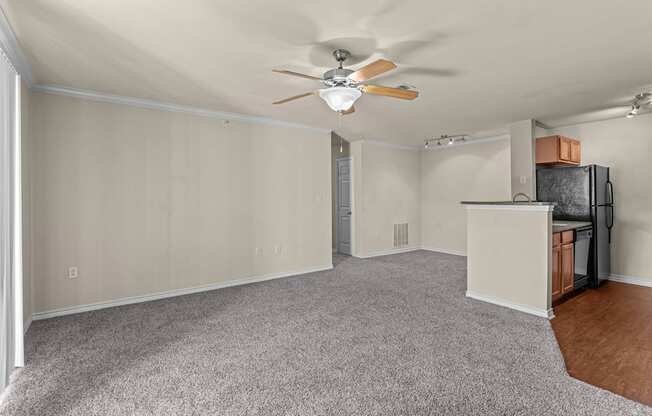 A room with a ceiling fan and a microwave on top of a counter.