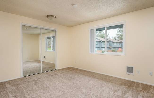 A room with a carpeted floor, a window, and a sliding glass door.