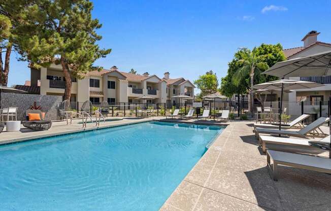 A large swimming pool surrounded by lounge chairs and umbrellas.