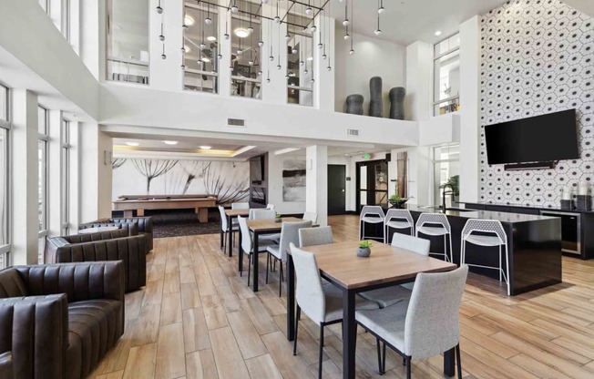 a large lobby with tables and chairs and a television