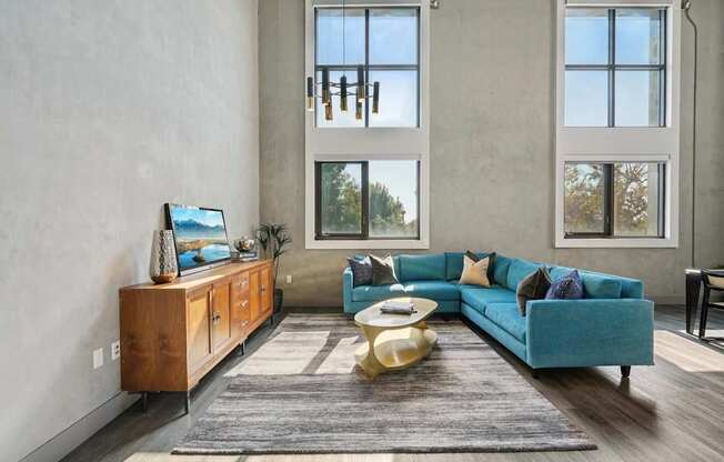 A living room with a blue couch and a wooden cabinet. at The Mansfield at Miracle Mile, California