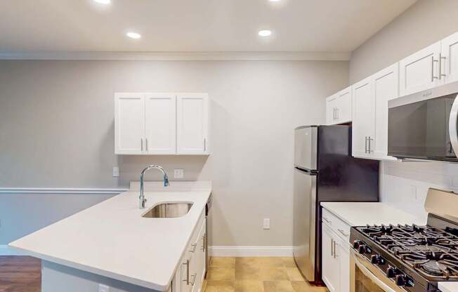 A kitchen with white cabinets and a black refrigerator.