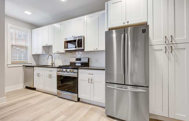 a white kitchen with stainless steel appliances and white cabinets