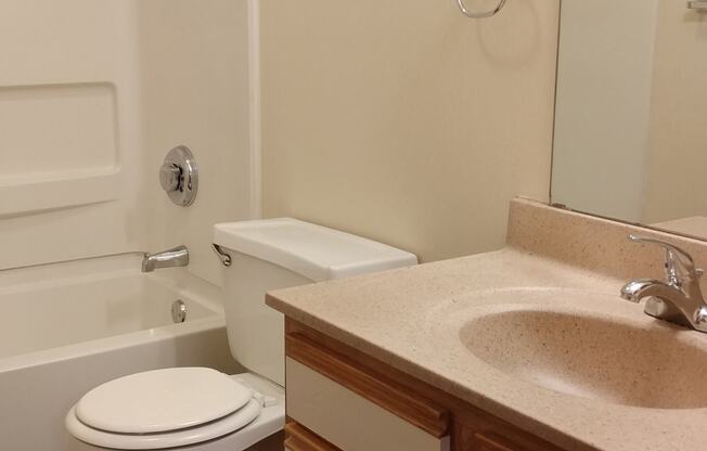 Image of bathroom with vanity, mirror, toilet, and tub