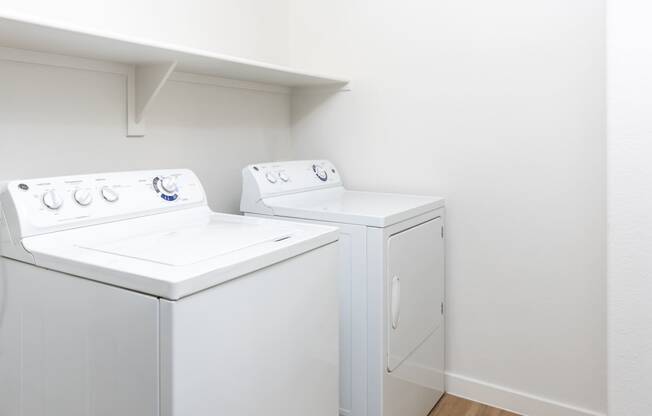 a white washer and dryer in a room with white walls and wood floors