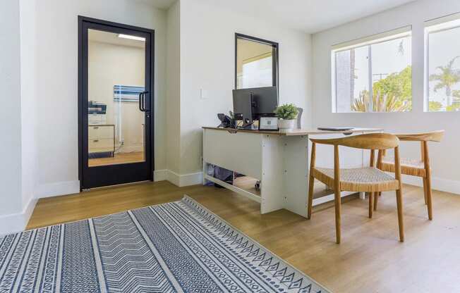 a living room with a desk and a door to a kitchen