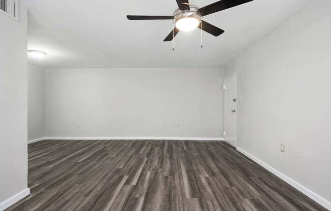 an empty living room with a ceiling fan