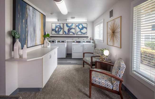 a living room with two chairs and a table and a kitchen
