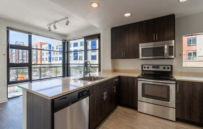 A modern kitchen with dark wood cabinets and stainless steel appliances.