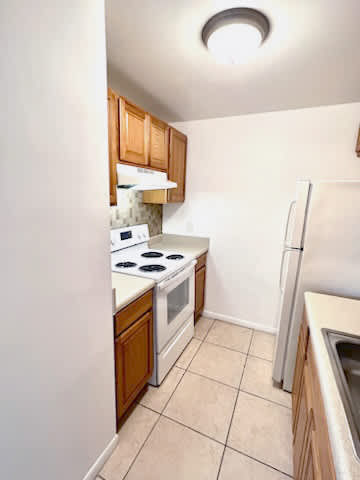 A kitchen with white appliances and wooden cabinets.