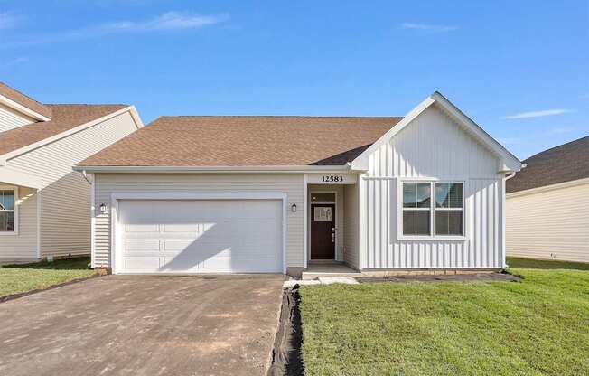 A white house with a brown roof and a garage door.