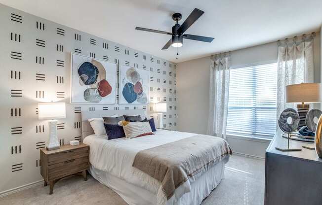 A bedroom with a bed, nightstand, and a ceiling fan.