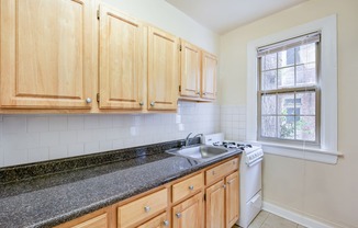 kitchen with tile floorings, wood cabinetry, refrigerator and gas range at 3151 mount pleasant apartments in washington dc