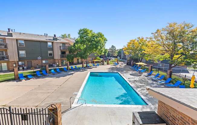 A swimming pool surrounded by blue chairs and apartment buildings.