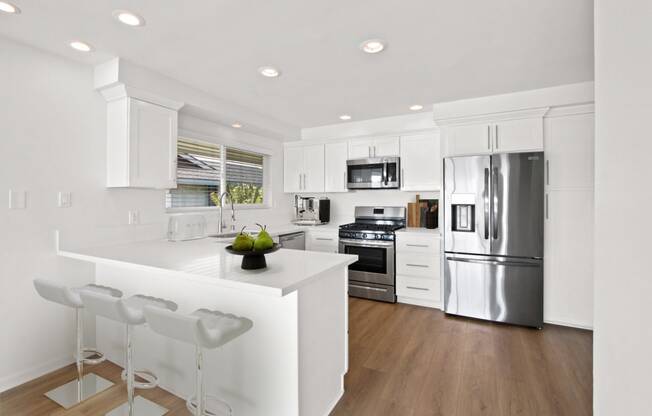 a white kitchen with a large island and stainless steel appliances