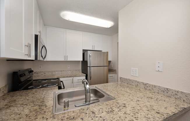 a kitchen with granite counter tops and a stainless steel refrigerator