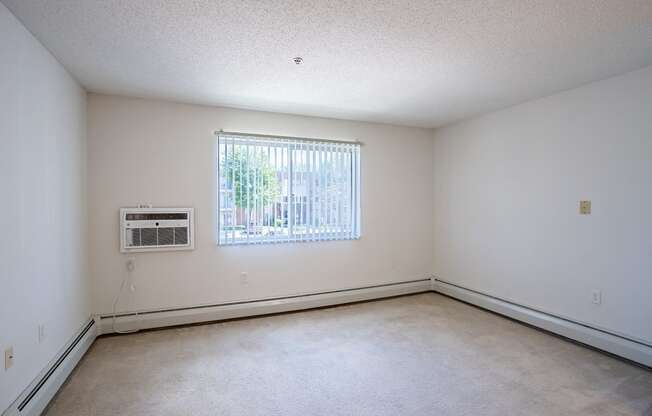 the living room of an empty house with a window and white walls. Eagan, MN Glen Pond Apartments