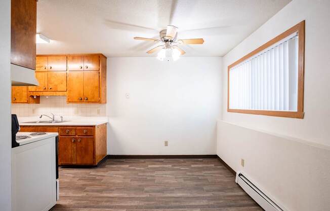 A kitchen with wooden cabinets and a ceiling fan. Fargo, ND Islander Apartments
