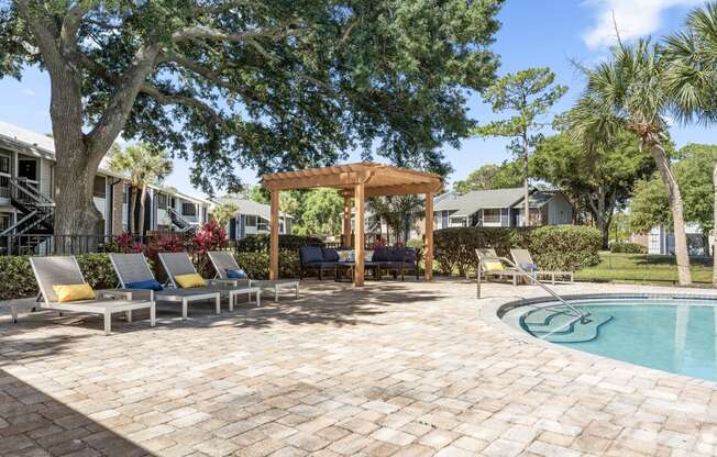 a backyard with a pool and patio with chairs and a gazebo