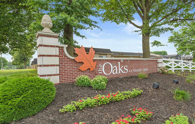 the sign at the entrance to the oaks campus with flowers and trees
