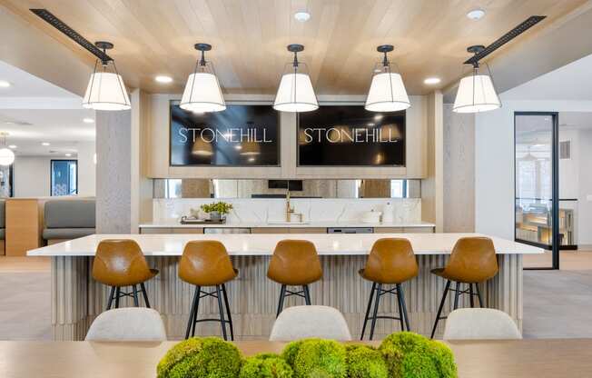 a modern kitchen with a bar and stools in front of a table with chairs