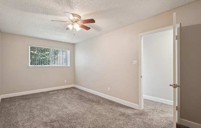 A room with a ceiling fan and a window with blinds.
