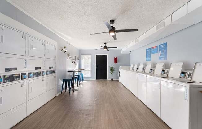 A laundry room with a washer and dryer on the wall and a table with two chairs.