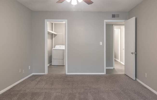 an empty room with a ceiling fan and a closet with a washer and dryer