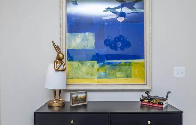 A black dresser with a gold lamp and books on top.