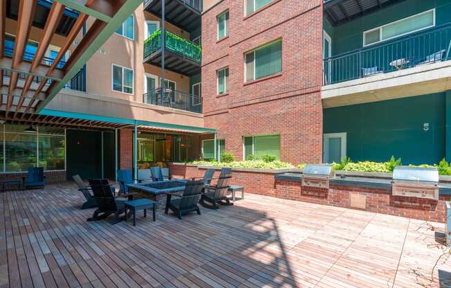 View of the resident fire pit lounge and patio area with bbq grills and red brick walls at Sylvan Uptown,Colorado, Denver