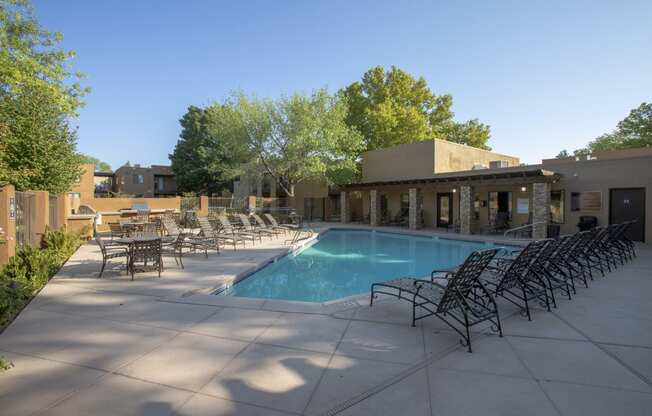 a swimming pool with chairs and a building in the background