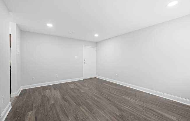 an empty living room with white walls and wood flooring