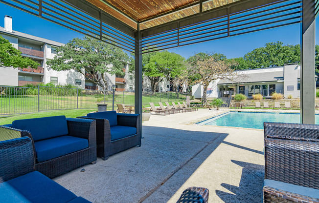 a covered patio with blue chairs and a pool