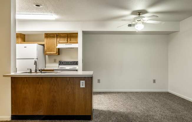 an empty living room with a kitchen and a ceiling fan at Pheasant Run in Lafayette, IN 47909