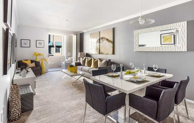 A modern dining room with a white table and grey chairs.