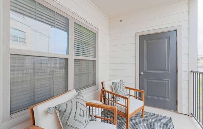 a front porch with a couch and chairs and a door
