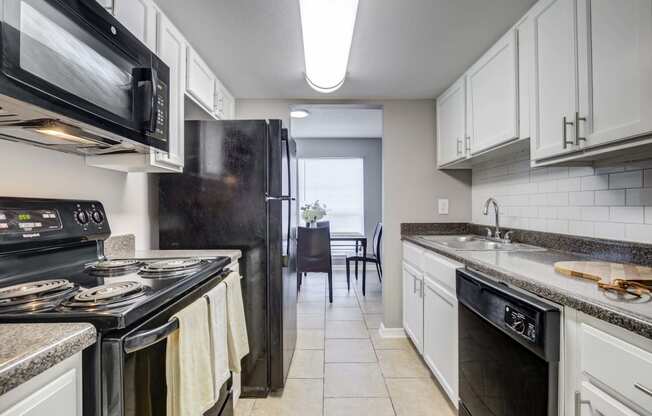 Westchase Apartments in Harvey LA photo of a kitchen with white cabinets and black appliances and a black refrigerator