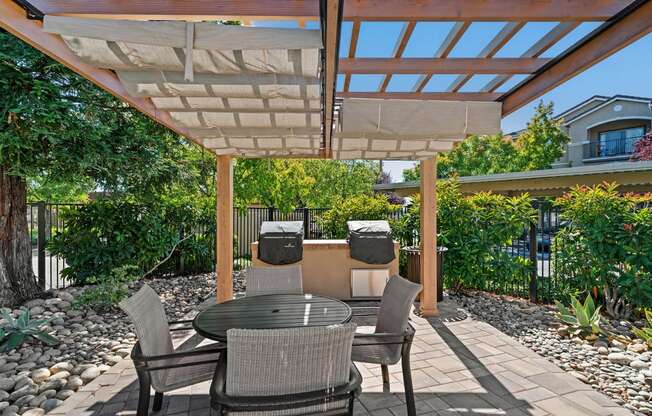a patio with a pergola and a table and chairs