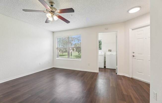 A room with a ceiling fan and a washing machine in it.