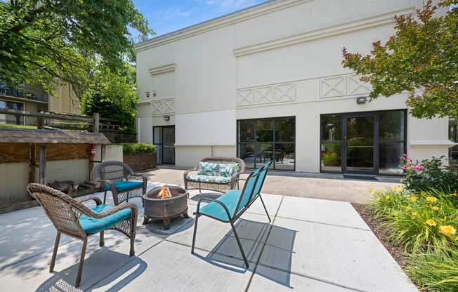 a patio with chairs and a fire pit and a building in the background