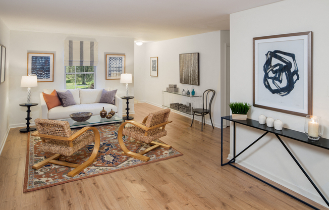 Furnished living room with a white couch and two wicker chairs sitting on top of an area rug