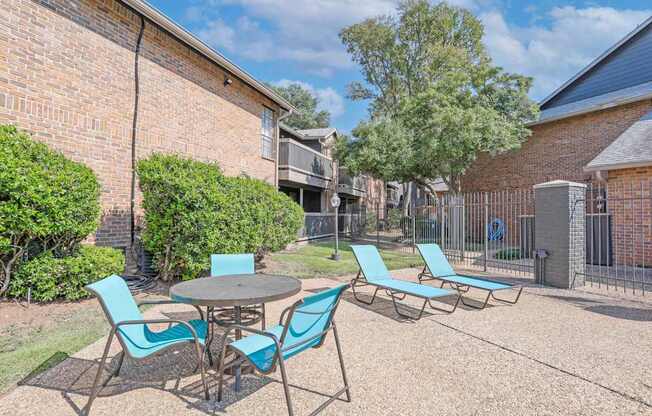 A pool area with a table and chairs is surrounded by brick apartment buildings at The Pearl apartments in Shreveport LA