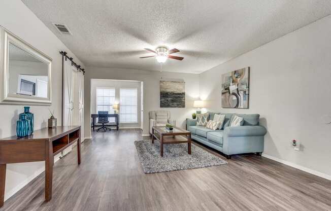 A living room with a blue couch and a wooden table.