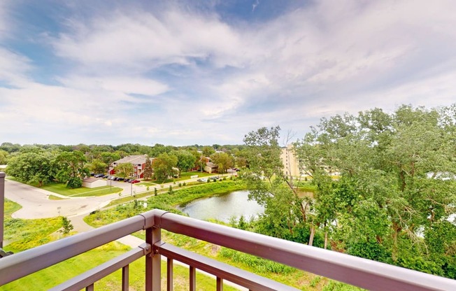 the view from the balcony of a condo with a pond and trees