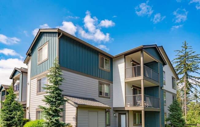 the view of two story apartment buildings with balconies and trees